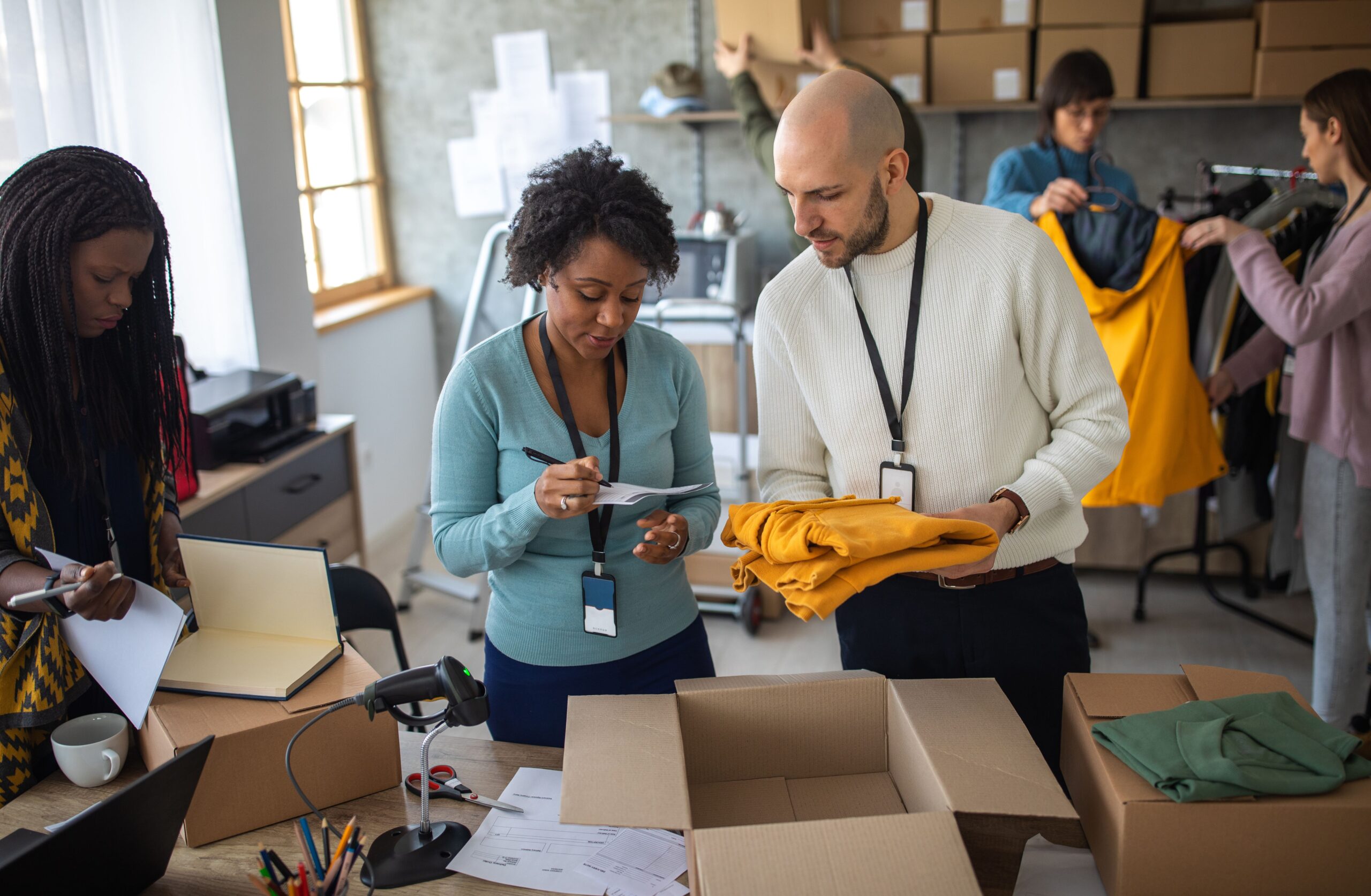 An Ecommerce team boxes up clothing products for shipment in an office.