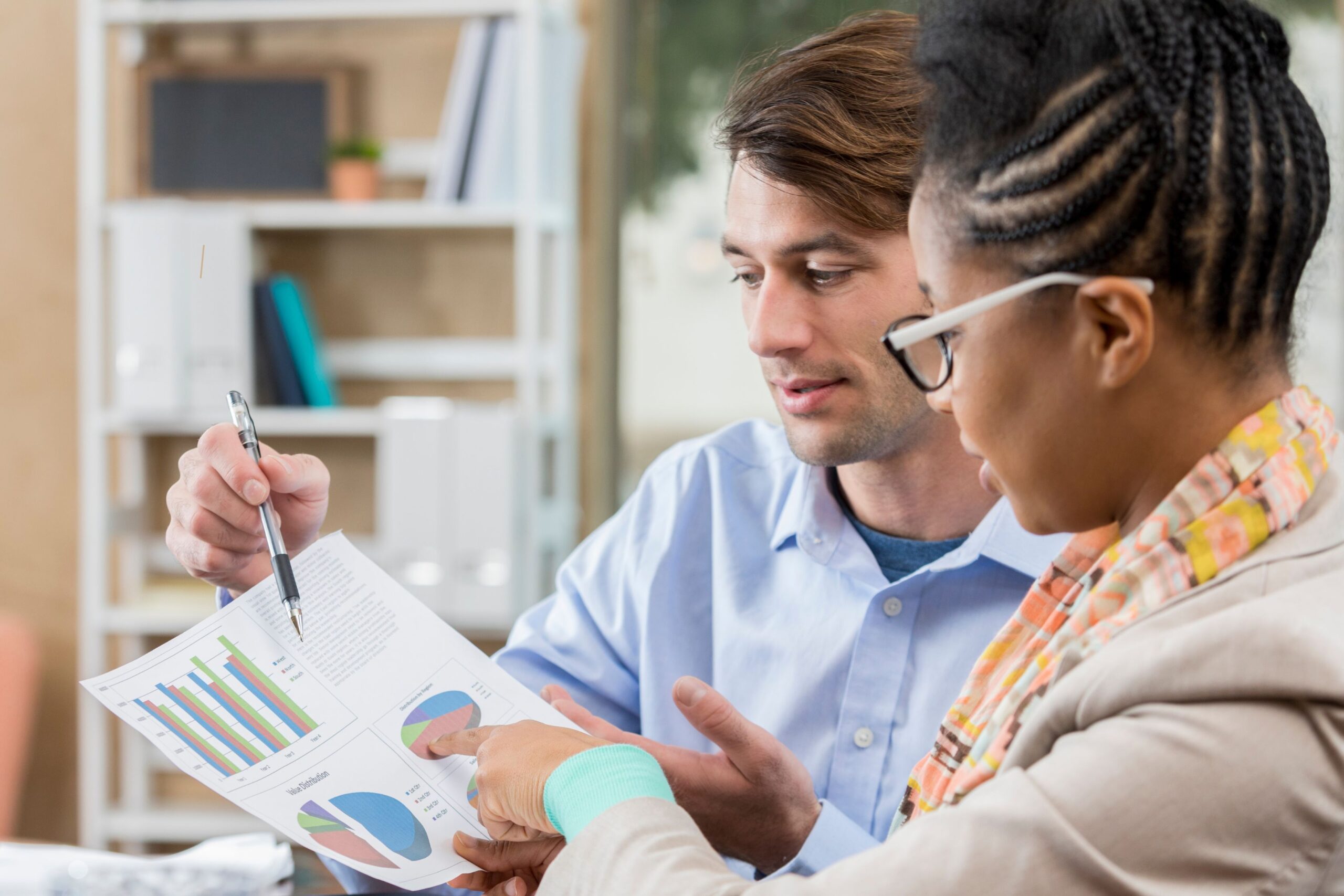 An accountant reviews accounts with a business owner in an office.