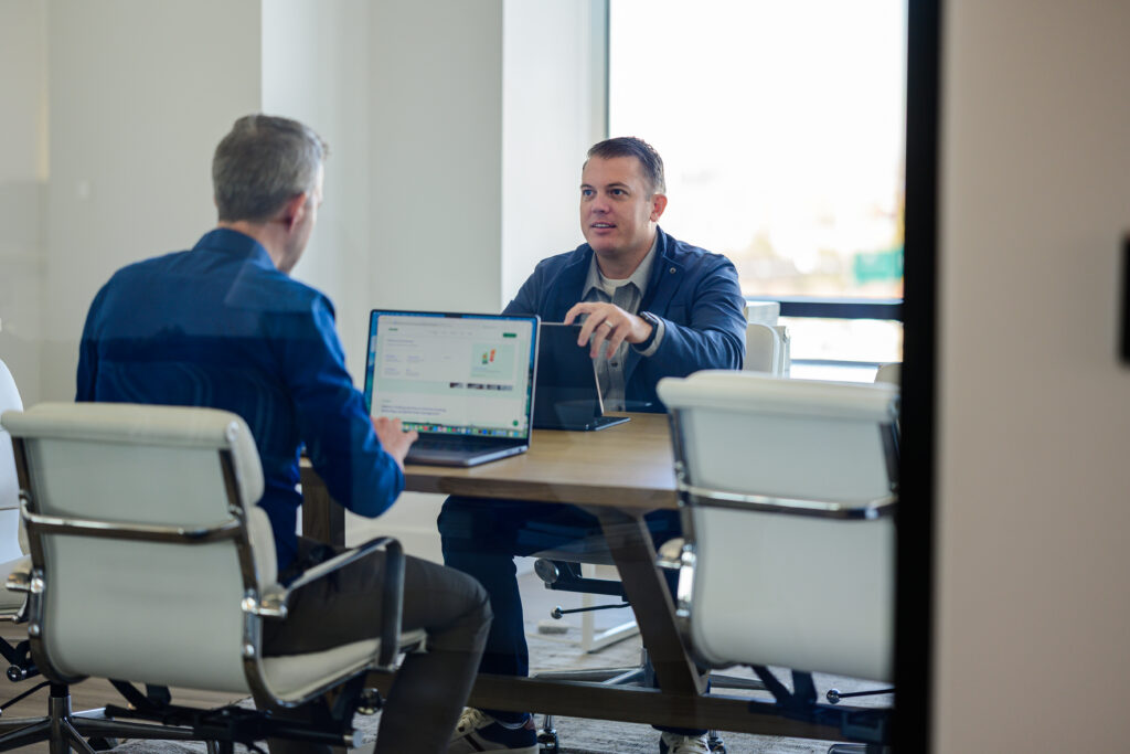 two men working and talking on an office desk